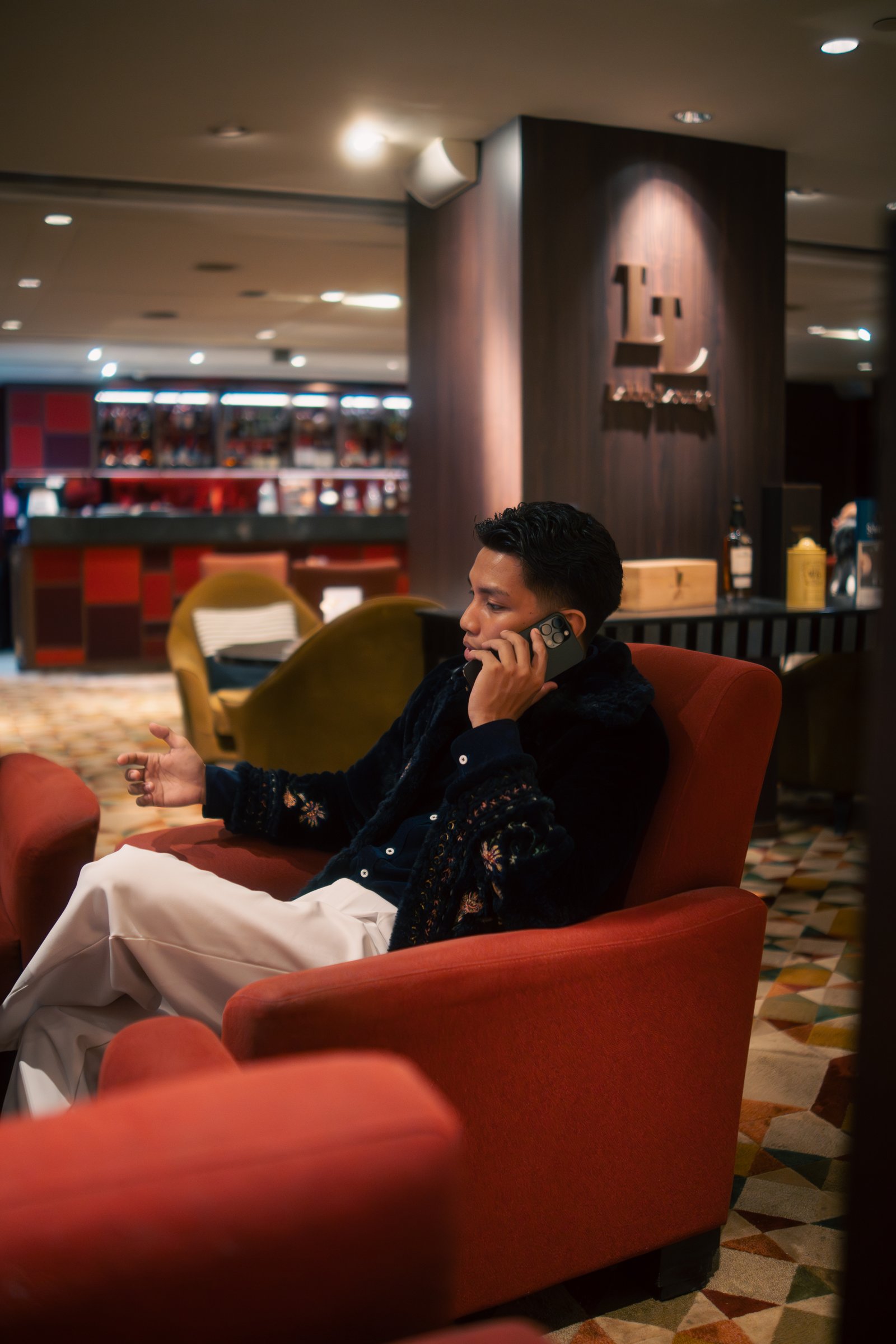 Lou Villaluna on a phone call in a hotel lounge, espresso in hand